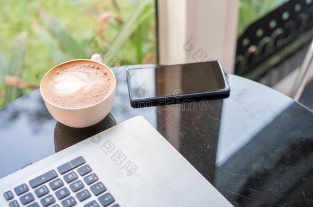 热的拿铁咖啡咖啡豆和便携式电脑和智能手机向玻璃表