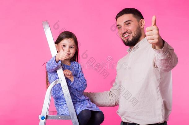 父亲和她小的<strong>女儿</strong>和<strong>拇指</strong>在上面越过粉红色的后台
