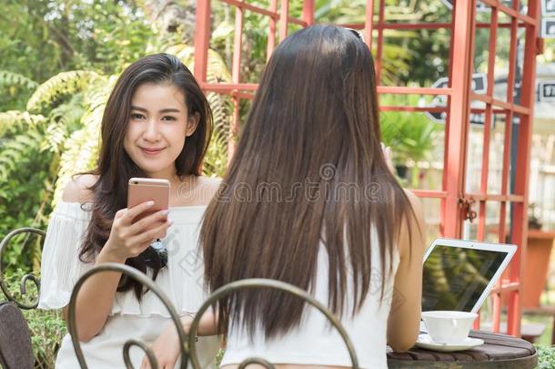 两个十几岁的女人相遇采用咖啡豆商店使用便携式电脑和智能手机