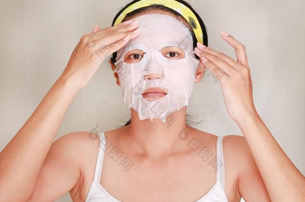 年幼的女人应用化妆品面部的面具采用指已提到的人浴室