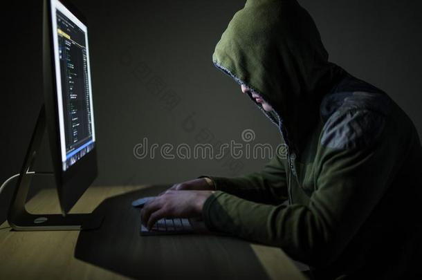 戴头巾的计算机黑客偷窃信息和personalcomputer个人计算机采用黑暗的房间