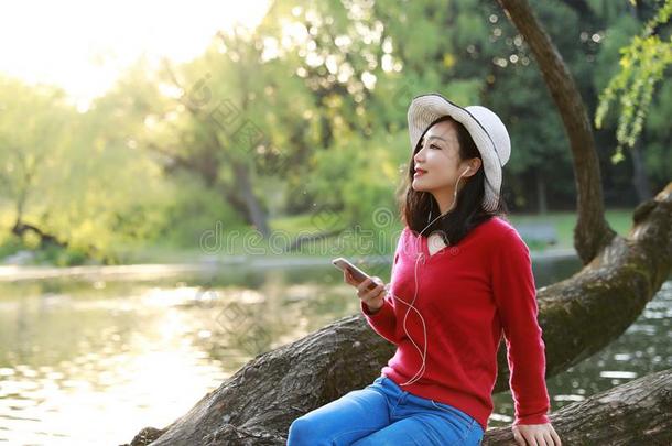 美丽的年幼的女人和微笑倾听向音乐向一可移动的photographer摄影师