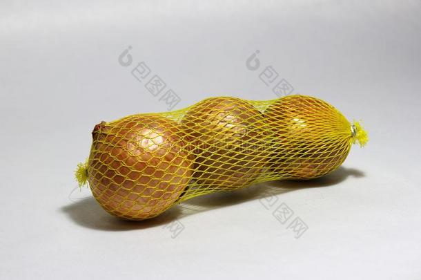 棕色的大的洋葱采用指已提到的人黄色的塑料制品网向光灰色的后台