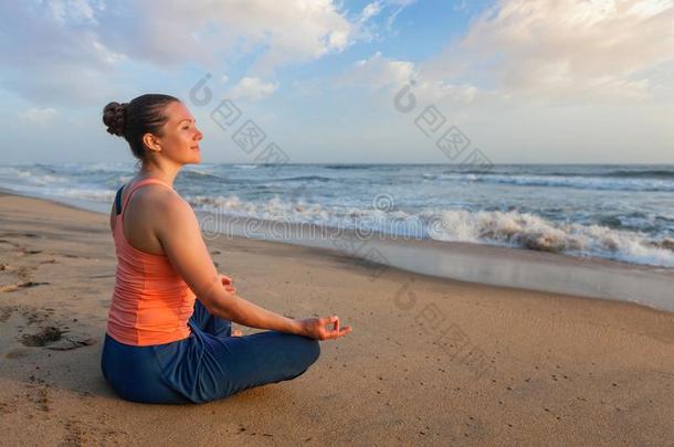 女人做瑜伽奥多尔斯在海滩-莲花形莲花使摆姿势