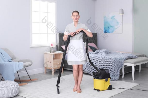 年幼的女人用真空吸尘器打扫地毯和真空清洁剂