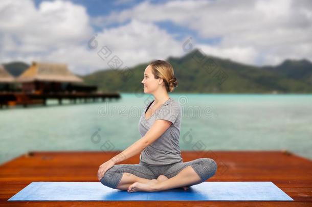 女人制造瑜伽采用扭成一束使摆姿势向席子在户外
