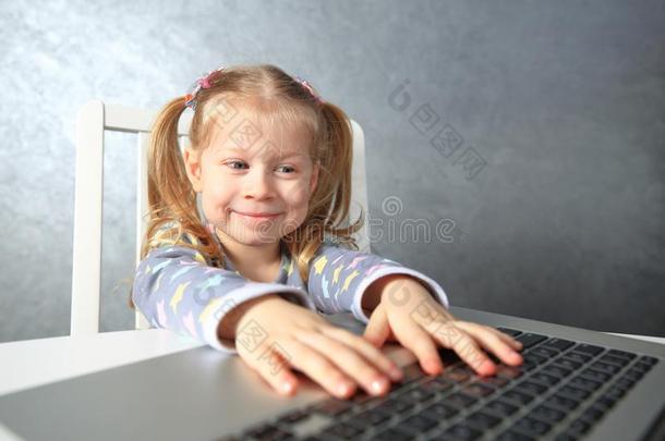 微笑的小的女孩学习计算机.女孩使用便携式电脑
