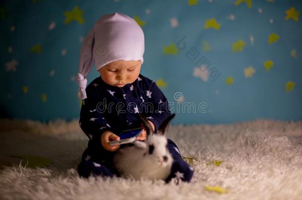 小的小孩,婴儿男孩和漂亮的白色的兔子和月亮向一蓝色