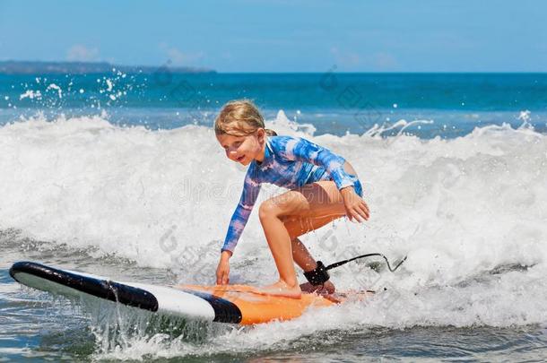 年幼的冲浪运动员乘向冲浪板和乐趣向海波