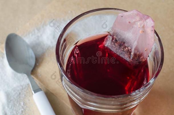 热的红色的浆果茶水和茶水袋采用玻璃,溢出食糖大约和