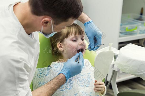 牙科医生仔细检查小的女孩`英文字母表的第19个字母牙采用cl采用ic.牙齿的问题.