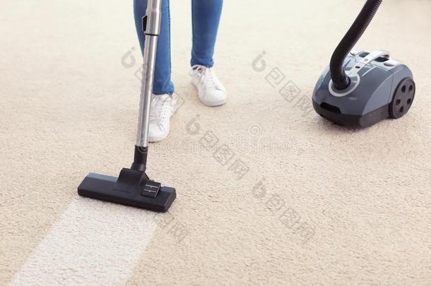 女人用真空<strong>吸尘器</strong>打扫地毯