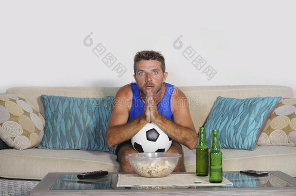 年幼的有魅力的男人观察<strong>足球游戏</strong>television电视机祈祷焦虑的一