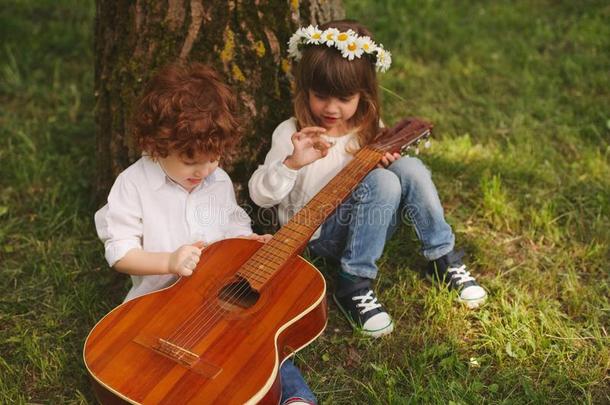 男孩和女孩演奏<strong>吉他</strong>采用夏公园