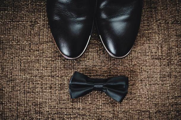 黑的鞋子和黑的蝴蝶躺向棕色的口袋布.