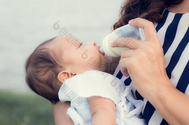 婴儿婴儿向存在联邦政府执法官员在旁边她mot她喝饮料奶从瓶子