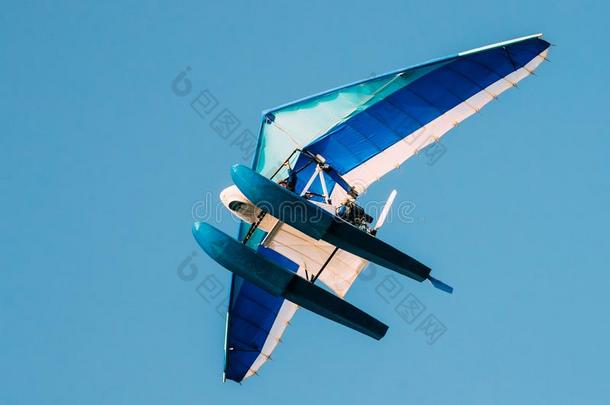 给装上发动机悬挂滑翔机飞行的向蓝色清楚的和煦的：照到阳光的天背景