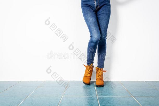 年幼的女孩蓝色牛仔裤棕色的鞋子墙白色的.