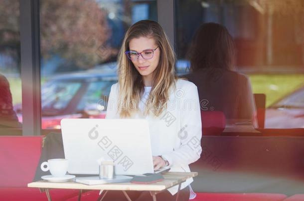 学生女人坐采用咖啡馆和便携式电脑,户外的射手