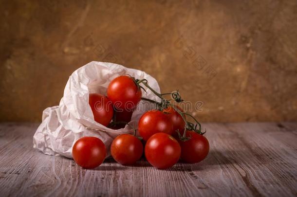多汁的新鲜的红色的番茄向木制的板采用纸袋