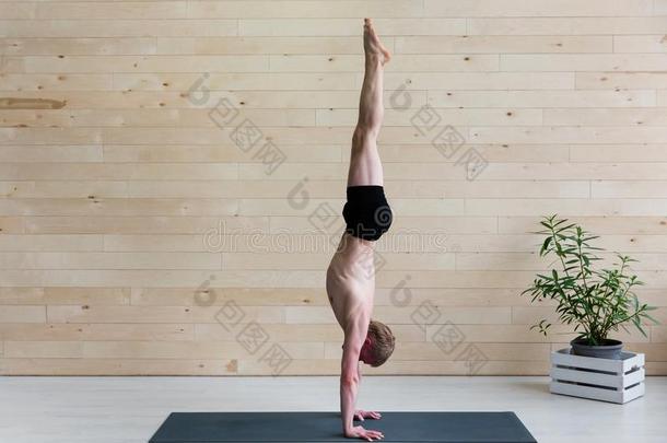 像运动家的男人练习瑜伽倒立瑜珈的任何一种姿势阿多穆卡Vriksh瑜珈的任何一种姿势