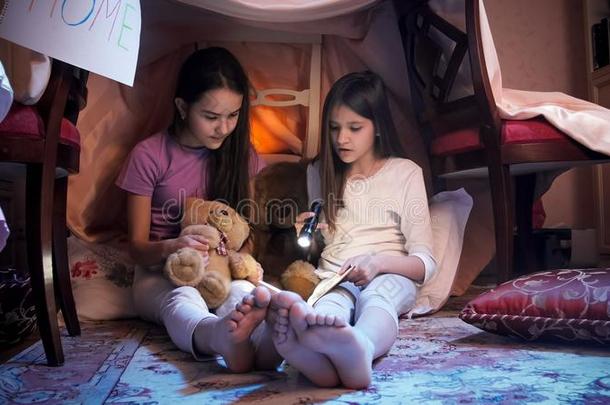 两个十几岁的女儿阅读使人惊慌的书采用卧室在夜