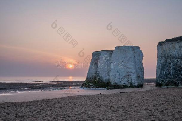 美丽的充满生机的日出越过岩石大量向海滩在低的潮汐