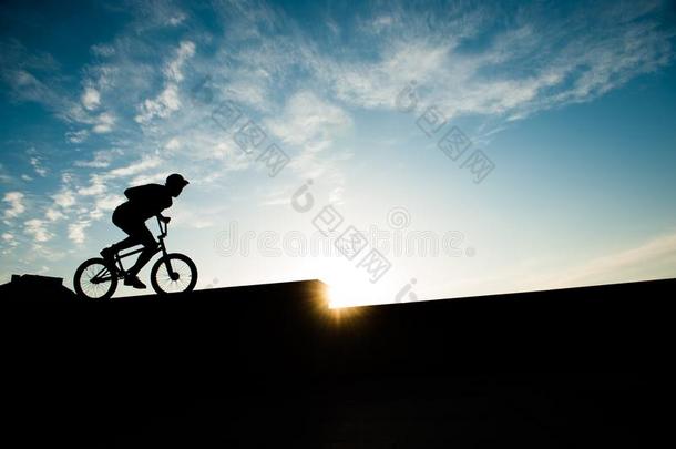 年幼的极端的男人骑马自行车向<strong>日</strong>落背景和<strong>科普</strong>斯
