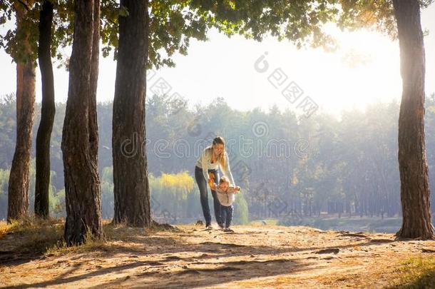 美丽的年幼的女人步行和她蹒跚行走的人儿子在秋标准