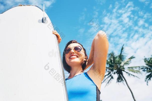 幸福的微笑的女人和冲浪板向热带的海滩