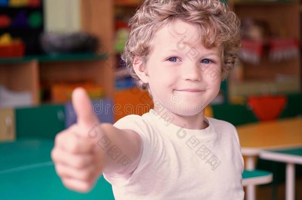 幸福的男孩展映拇指在上面手势向<strong>幼儿园背景</strong>.