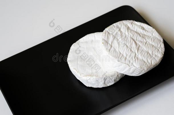两个正面朝上的关于法国Camembert村所产的软质乳酪或法国布里白乳酪奶酪采用黑的正<strong>方形盘子</strong>.顶