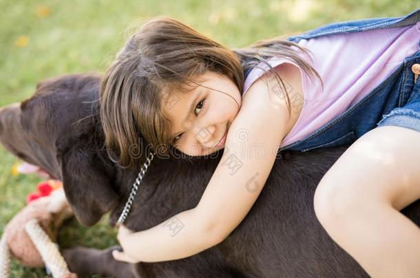 无辜的小的女孩热烈地拥抱宠物狗