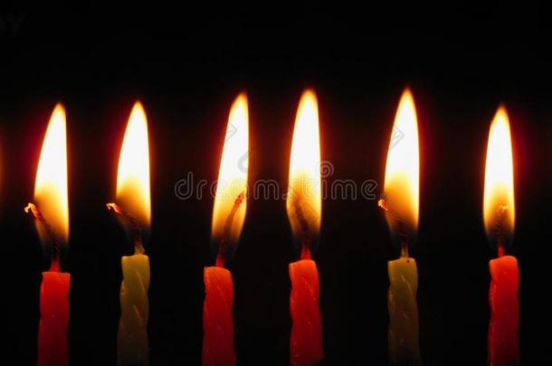 颜色鲜艳的生日蜡烛燃烧的反对黑的背景