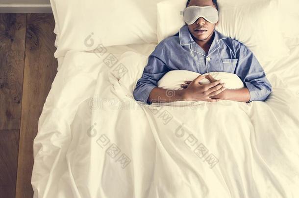 黑的男人睡眠向床和眼睛面具