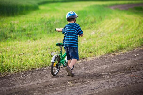 小的男孩步行上坡的和他的自行车向乡下的风景