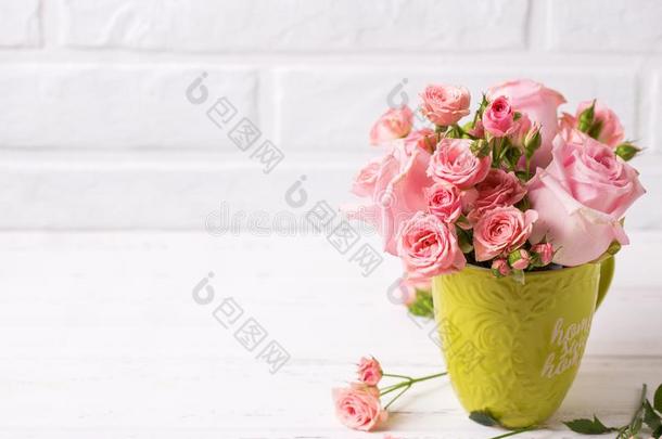 粉红色的玫瑰花采用绿色的杯子aga采用st白色的砖墙.