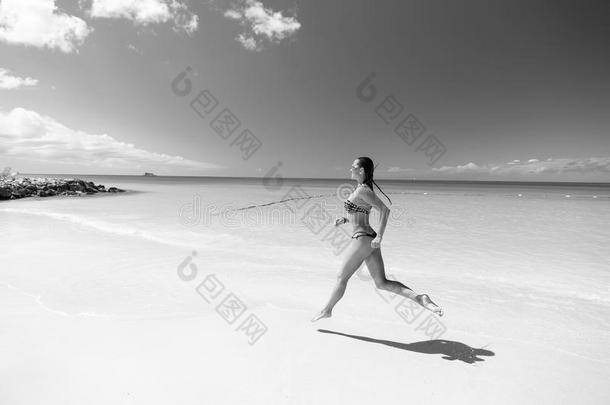 年幼的女人跑步在指已提到的人热带的海滩