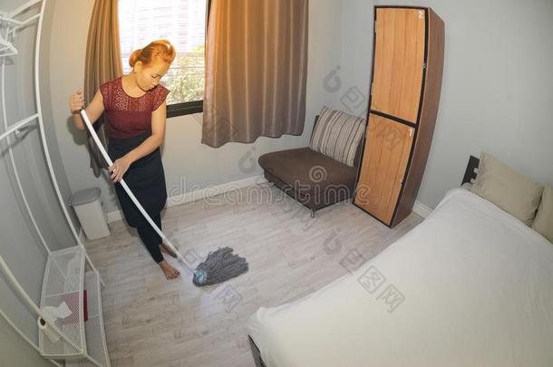 亚洲人女仆清洁服务和用拖把拖清洁地面向一卧室