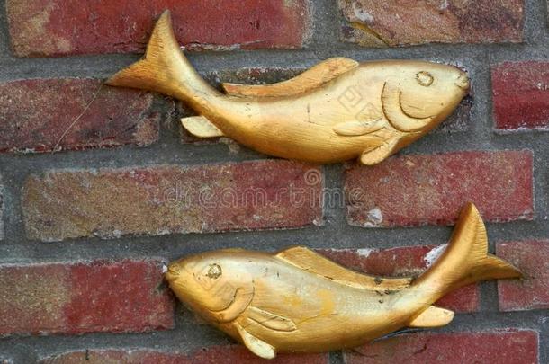 两个有雕刻的鱼向砖墙