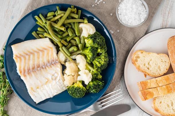烘烤制作的海鱼鳕鱼肉片和蔬菜向蓝色盘子,面包,