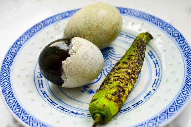 两个中国人百年卵和绿色的红辣椒向盘子