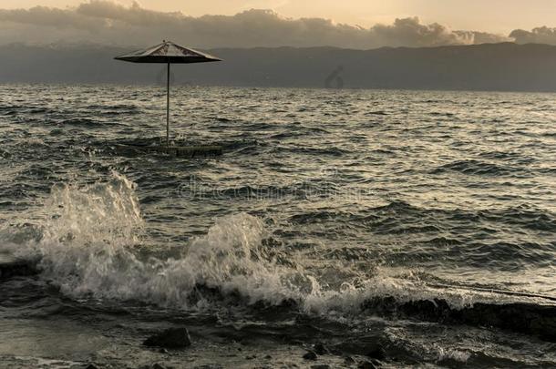 海滩雨伞采用指已提到的人湖奥赫里德在有暴风雨的wea指已提到的人r日落