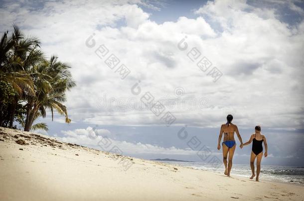 母亲和女儿步行向指已提到的人太古的热带的海滩