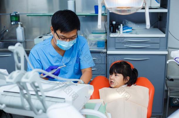 小的女孩有样子的小心的在指已提到的人牙科医生.医生和他的人名