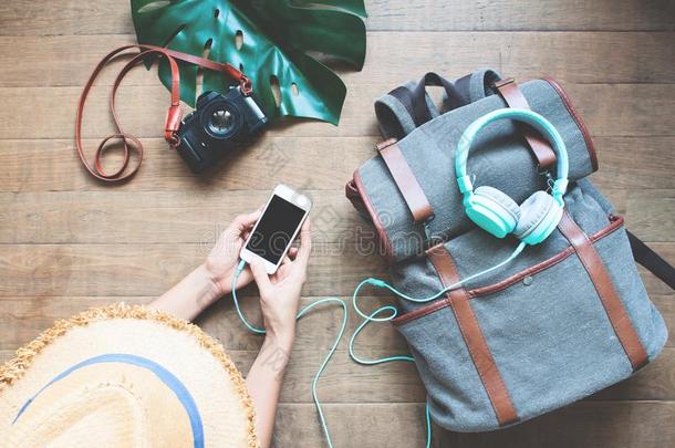 顶看法旅行者女人使用智能手机和耳机向备份