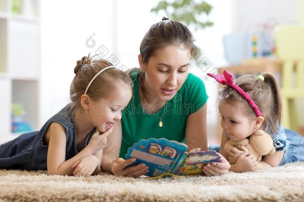 漂亮的母亲和她两个女儿孩子们阅读故事在一起