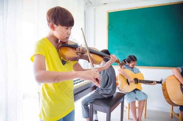 年幼的男孩演奏小提琴采用教室