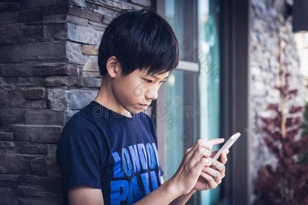 亚洲人男孩十几岁的青少年使用智能<strong>手机</strong>,户外的<strong>日</strong>光.
