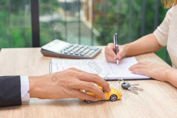 女人签署汽<strong>车贷</strong>款协定合同和汽车钥匙和卡库